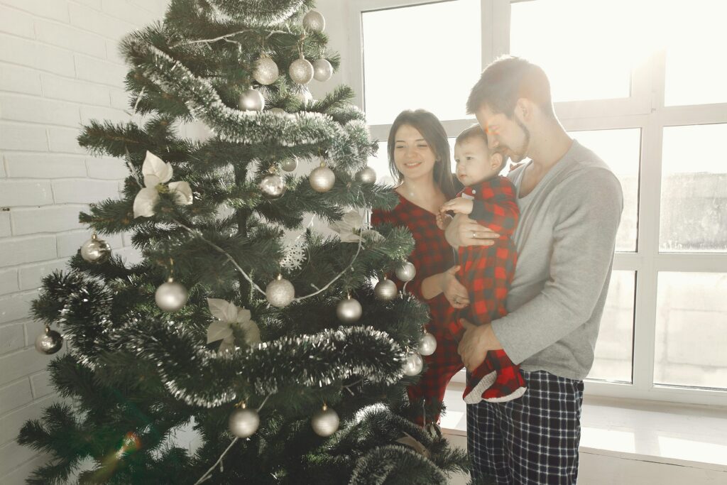 Familie bei Weihnachten mit Baby zuhause am Tannenbaum