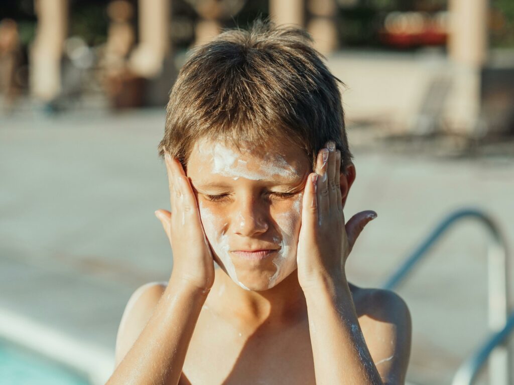 Junge trägt Sonnencreme auf