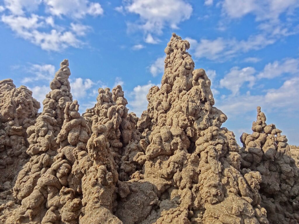 Schlickertürme aus nassem Sand formen eine Sandburg